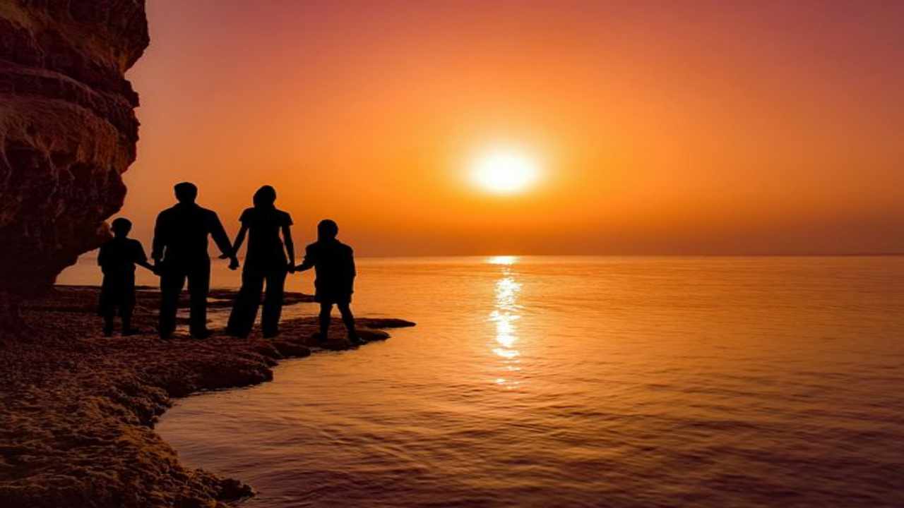 Famiglia che guarda il tramonto al mare