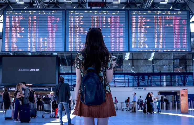 Donna in aeroporto che osserva il tabellone degli arrivi e delle partenze