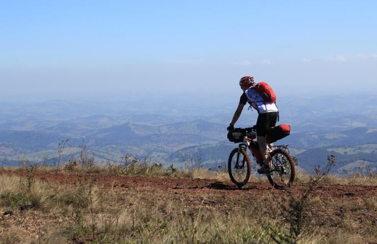 Cicloturista sulla sua bicicletta, con le montagne sullo sfondo