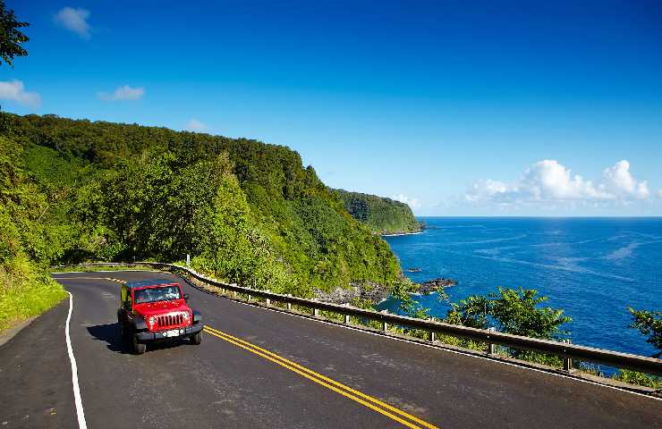 Macchina che percorre una strada che costeggia la costa alle Hawaii