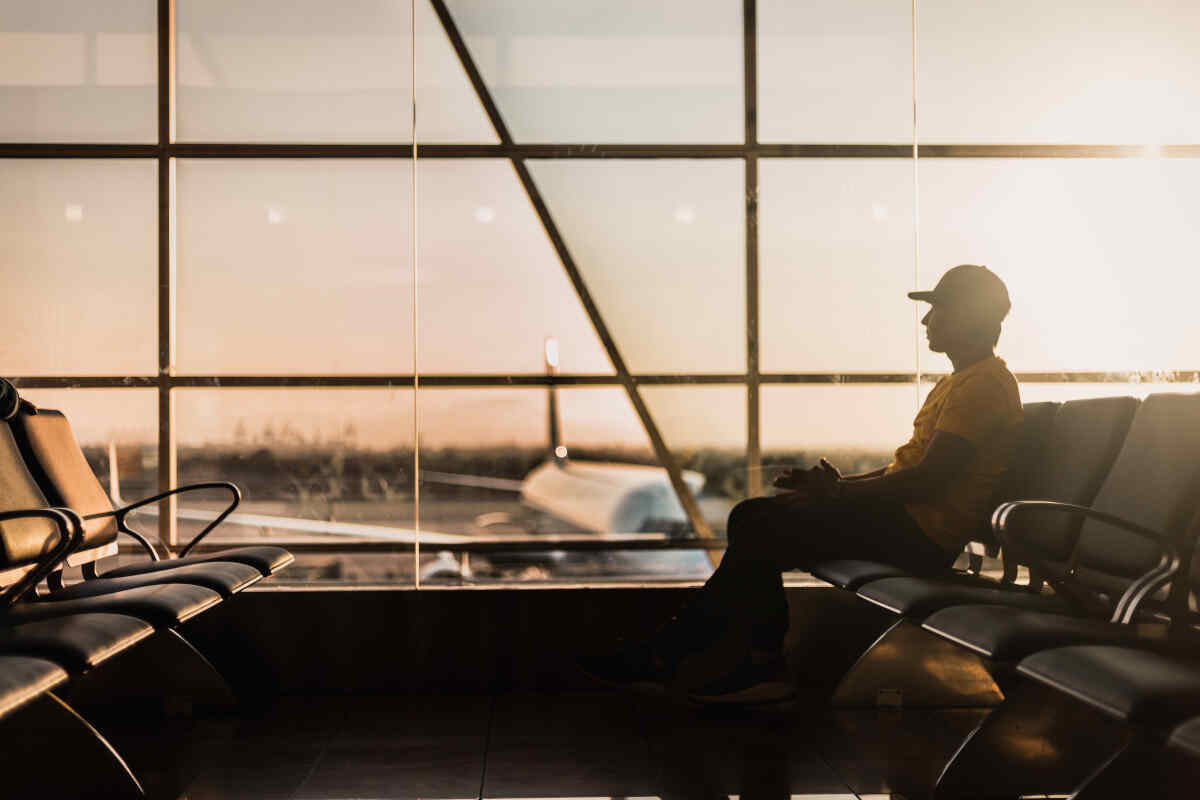 Un uomo seduto in aeroporto alla luce del tramonto