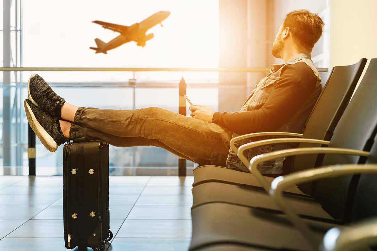 un ragazzo con valigia in una sala d'aspetto dell'aeroporto