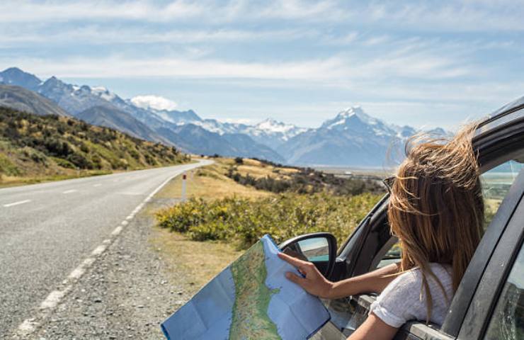 Ragazza con una mappa che utilizza l'auto per spostarsi in Nuova Zelanda
