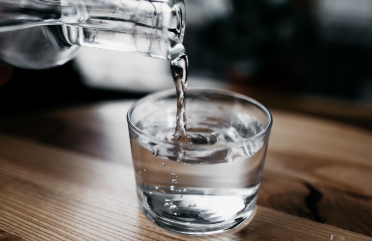 Acqua versata in un bicchiere da una bottiglia