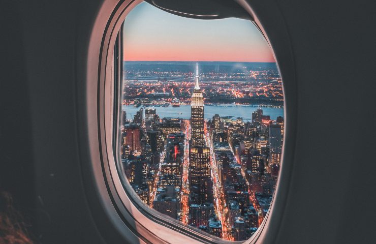 Città illuminata vista di notte dal finestrino di un aereo in volo